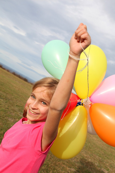 Menina segurando balões no campo
 - Foto, Imagem
