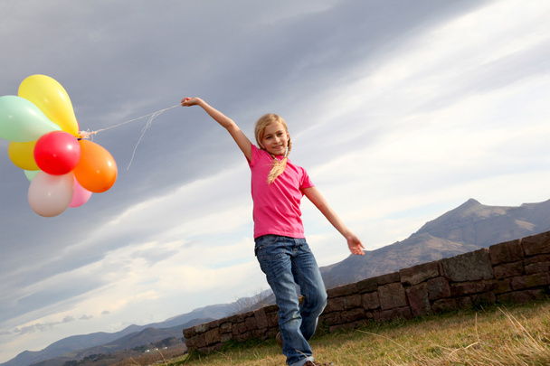 Little girl holding balloons out in the countryside - Valokuva, kuva