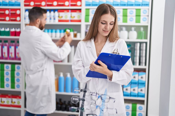 Чоловік і жінка фармацевти посміхаються впевнено писати на документі в аптеці
 - Фото, зображення
