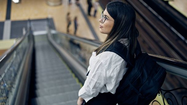 Jovem bela mulher hispânica em pé na escada rolante usando mochila na estação de metrô de Madrid - Foto, Imagem