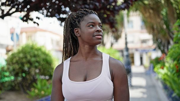 Afro-Amerikaanse vrouw op zoek naar de kant met serieuze expressie op park - Foto, afbeelding