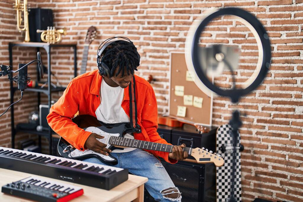 Αφροαμερικανός καλλιτέχνης έχοντας ηλεκτρική κιθάρα σε απευθείας σύνδεση μάθημα στο στούντιο μουσικής - Φωτογραφία, εικόνα