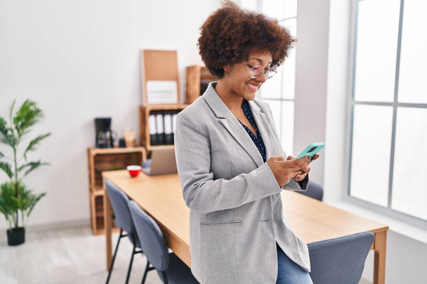 Afrikaans amerikaanse vrouw zakenman met behulp van smartphone op kantoor - Foto, afbeelding
