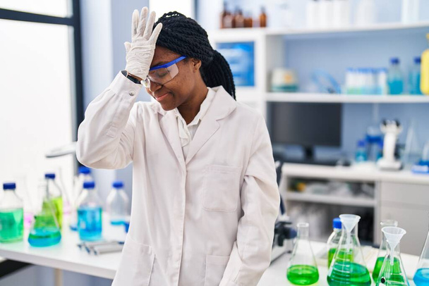 Afroamerikanerin, die im wissenschaftlichen Labor arbeitet, überrascht mit der Hand auf dem Kopf für Fehler, erinnere dich an Fehler. Vergessenes, schlechtes Gedächtnis.  - Foto, Bild