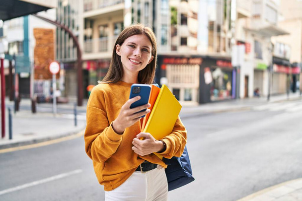 Sokakta akıllı telefon kullanan genç sarışın kız öğrenci. - Fotoğraf, Görsel
