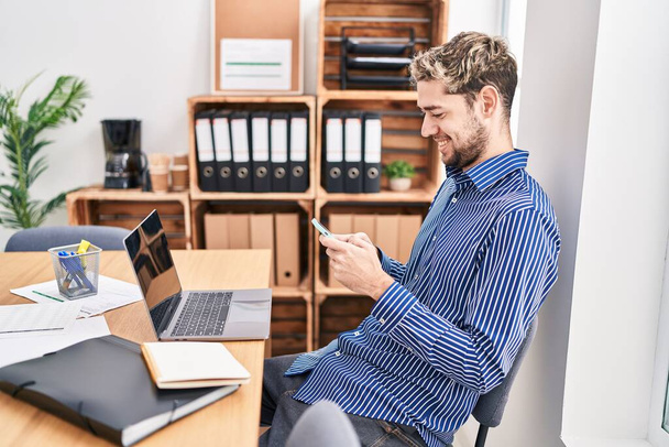 Trabajador de negocios joven usando computadora portátil y teléfono inteligente en la oficina - Foto, Imagen