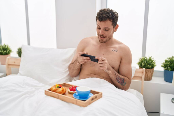 Giovane uomo ispanico fare foto a colazione in camera da letto - Foto, immagini