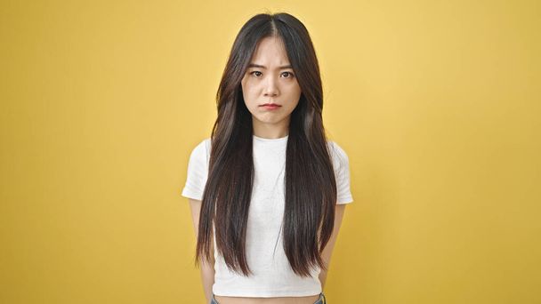 Jovem chinesa de pé com expressão relaxada sobre fundo amarelo isolado - Foto, Imagem
