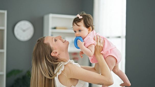 Mother and daughter hugging each other sucking toy at home - Photo, Image