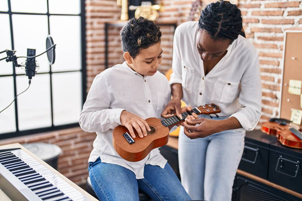 Africano americano madre e hijo estudiante aprendizaje jugar ukelele en estudio de música - Foto, imagen