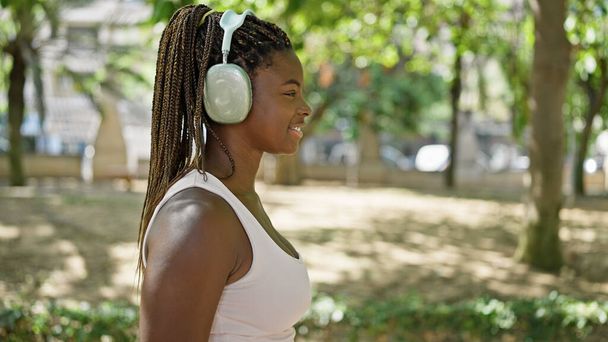 Afro-Amerikaanse vrouw luisteren naar muziek glimlachen in het park - Foto, afbeelding