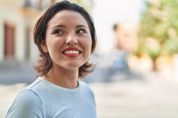 Young hispanic woman smiling confident looking to the sky at street - Photo, image