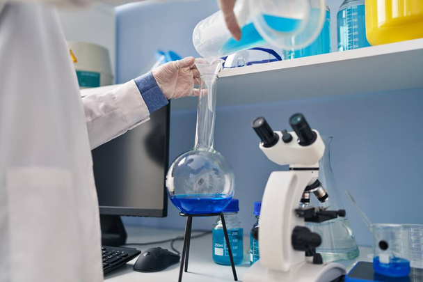 Nuori blondi nainen tiedemies kaataa nestettä koeputkeen laboratoriossa - Valokuva, kuva