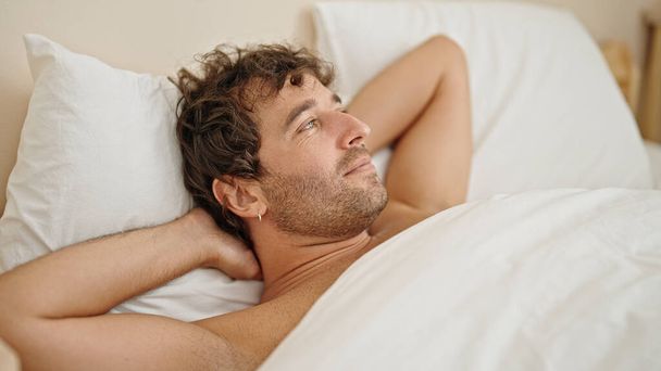 Jovem hispânico homem relaxado na cama sem camisa no quarto - Foto, Imagem