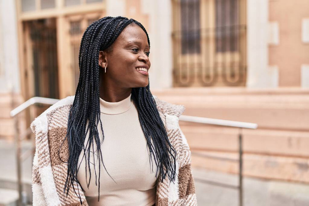 Африканская американка улыбается уверенно глядя в сторону улицы - Фото, изображение