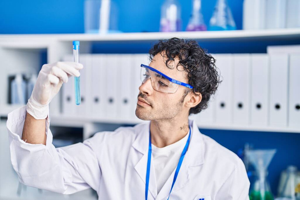 Joven científico hispano sosteniendo tubo de ensayo en laboratorio - Foto, imagen