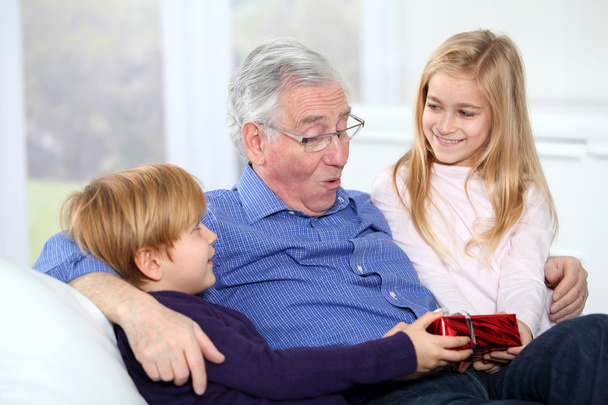 Kids giving birthday gift to their grandfather - Foto, Imagen