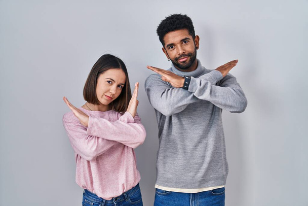Fiatal spanyol pár áll együtt elutasítás kifejezés keresztbe karok csinál negatív jel, dühös arc  - Fotó, kép