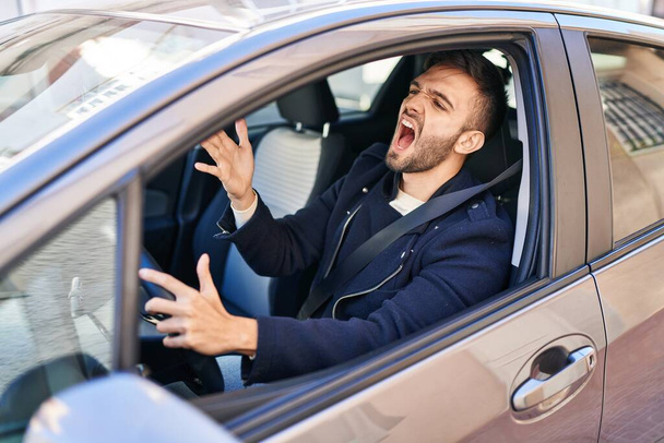 Молодой латиноамериканец стресс вождение автомобиля на улице - Фото, изображение