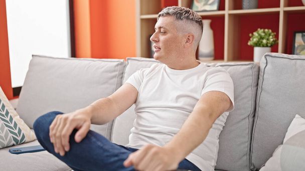 Mladý běloch sedí na pohovce s vážnou tváří doma - Fotografie, Obrázek