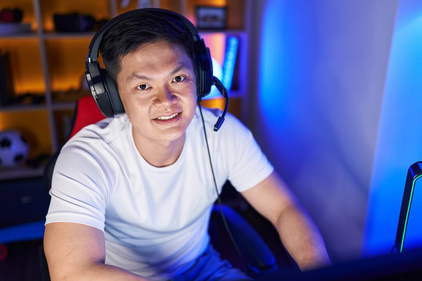 Молодой китайский стример играет в видеоигры на компьютере в игровой комнате - Фото, изображение