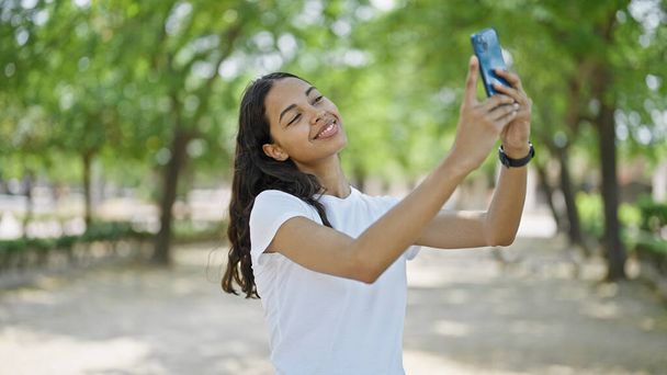 Afrikai amerikai nő mosolyog magabiztos, hogy szelfi az okostelefon a parkban - Fotó, kép