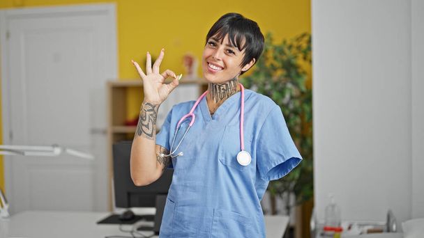 Spaanse vrouw met geamputeerde arm arts doet ok gebaar in de kliniek - Foto, afbeelding