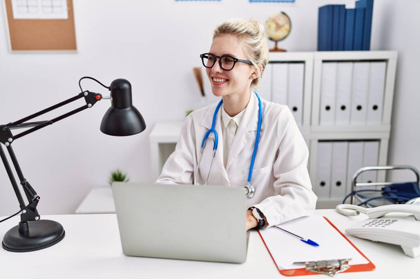 Mujer joven rubia médico utilizando el ordenador portátil que trabaja en la clínica - Foto, imagen