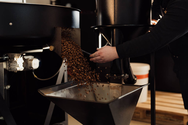 Crop anonyymi miespuolinen työntekijä painamalla vipua ja paahdettuja kahvipapuja kaatamalla release kouru moderni tehdas - Valokuva, kuva