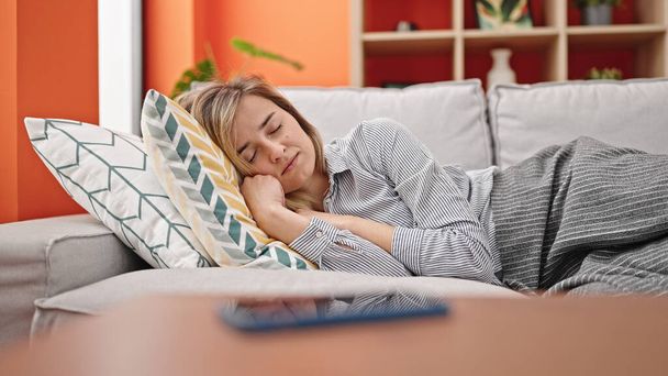 Young blonde woman lying on sofa sleeping at home - Fotografie, Obrázek