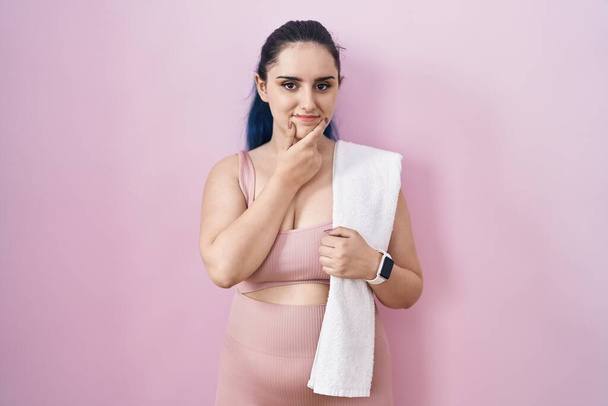 Young modern girl with blue hair wearing sportswear over pink background with hand on chin thinking about question, pensive expression. smiling and thoughtful face. doubt concept.  - Foto, immagini