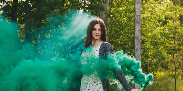 Girl with smoke bomb makes saturated green clouds of smoke. - Photo, Image