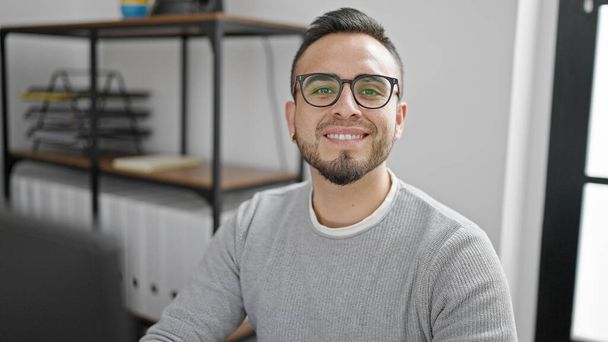 Trabajador de negocios hispano usando computadora sonriendo en la oficina - Foto, imagen