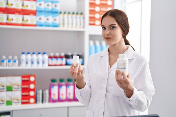 Jeune femme pharmacienne tenant bouteille de pilules à la pharmacie - Photo, image