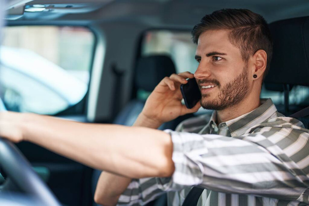 Nuori valkoihoinen mies puhuu älypuhelimella istuu autolla kadulla - Valokuva, kuva