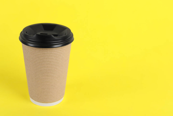 Paper cup with plastic lid on yellow background, space for text. Coffee to go - Foto, Imagen