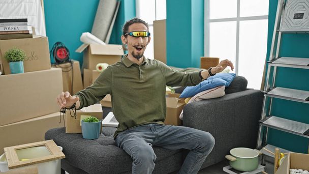 若いですヒスパニック男遊びビデオゲームを使用して仮想現実の眼鏡で新しい家 - 写真・画像