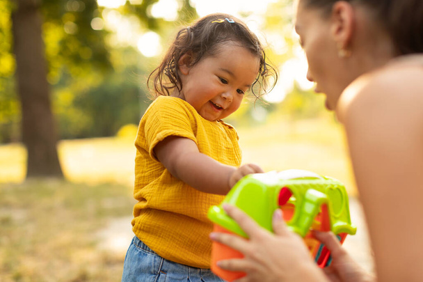 Asijské maminka dávat ji dítě dcera umělá hračka hrát venku na léto den. Zaostřeno, Selektivní Soustředění. Dětské hřiště Zábavné aktivity a sbližování pro maminku a batole dítě - Fotografie, Obrázek