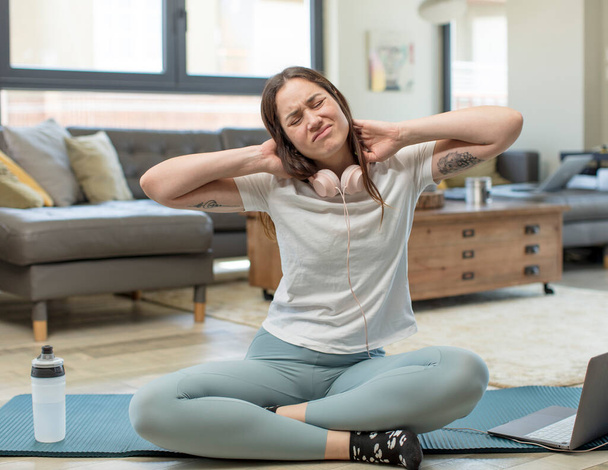 jeune femme adulte pratiquant le yoga se sentant anxieux, malade, malade et malheureux, souffrant d'une douleur au cou - Photo, image