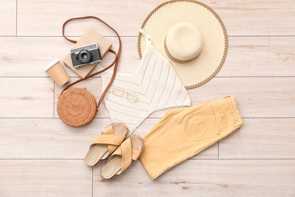 Літній одяг з аксесуарами, чашка кави та фотоапарат на світлій дерев'яній підлозі
 - Фото, зображення