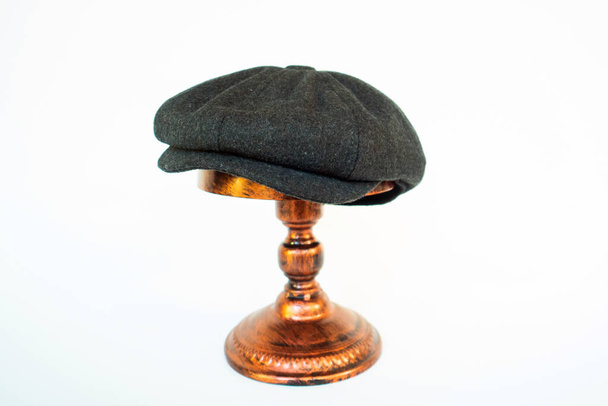 Zdjęcie klasycznego katalogu kapelusza z ośmiopanelową nasadką gazeciarza w przytulnym wełnianym kolorze czarnym o północy, zamontowanym na brązowej głowicy manekina na białym tle studia - Zdjęcie, obraz