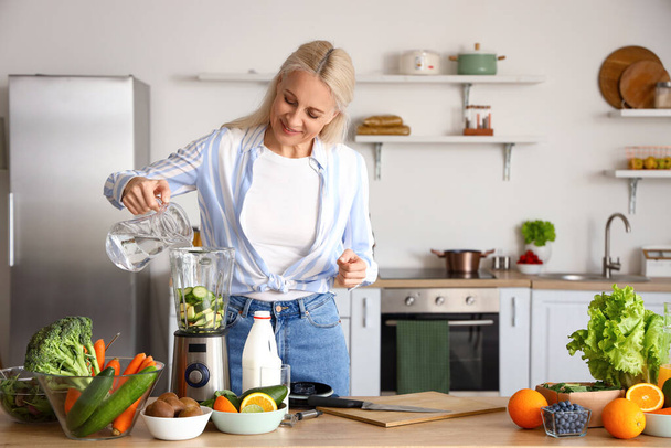 Donna matura che fa frullato vegetale sano in cucina - Foto, immagini