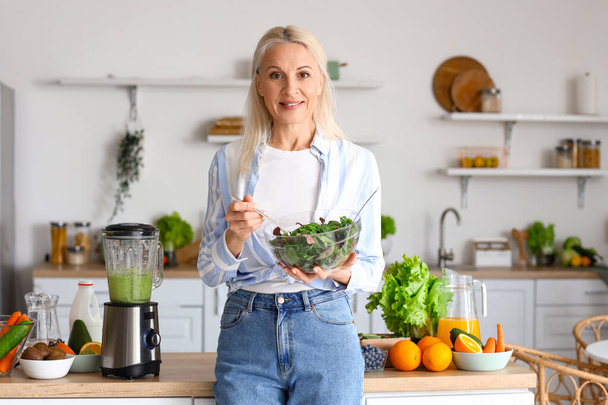 Mujer madura con tazón de ensalada de verduras en la cocina - Foto, imagen