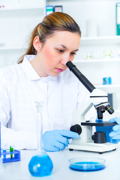 Woman working with a microscope in a lab - Zdjęcie, obraz