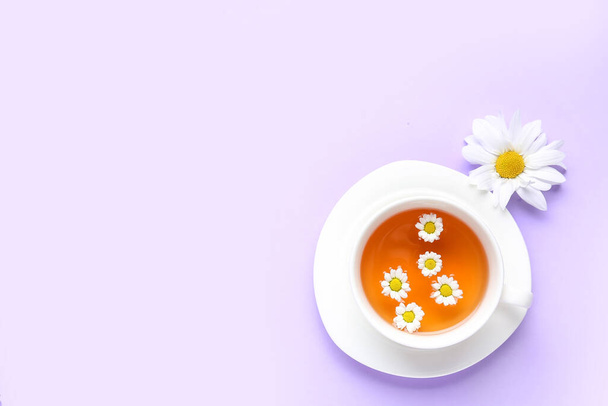 Κύπελλο του φυσικού χαμομηλιού τσάι με λουλούδι σε λιλά φόντο - Φωτογραφία, εικόνα