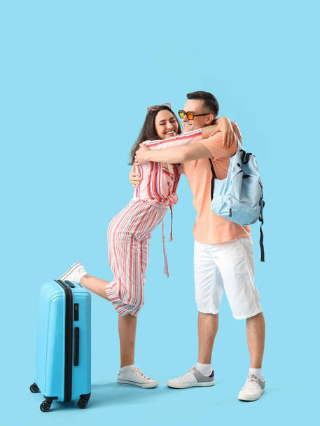 Молодая пара с сумками, обнимающимися на синем фоне - Фото, изображение