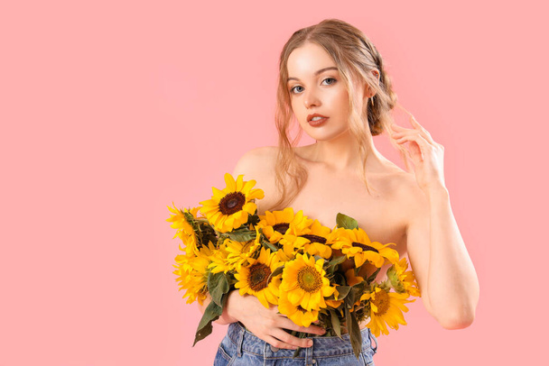 Young woman with beautiful sunflowers on pink background - Photo, image