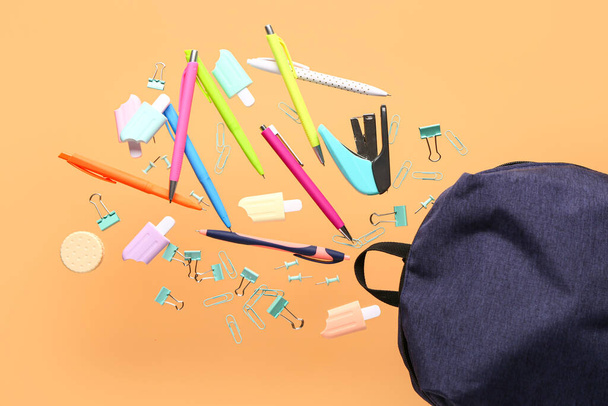 Κομψή σχολική τσάντα πλάτης με διαφορετικά χαρτικά που φέρουν στο φόντο χρώμα - Φωτογραφία, εικόνα
