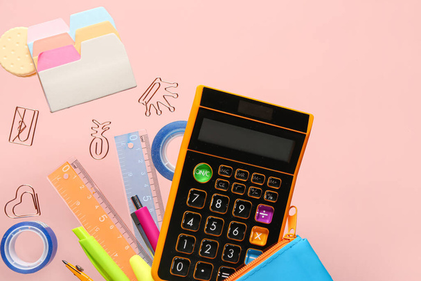 Different stationery with calculator flying on pink background - Photo, Image