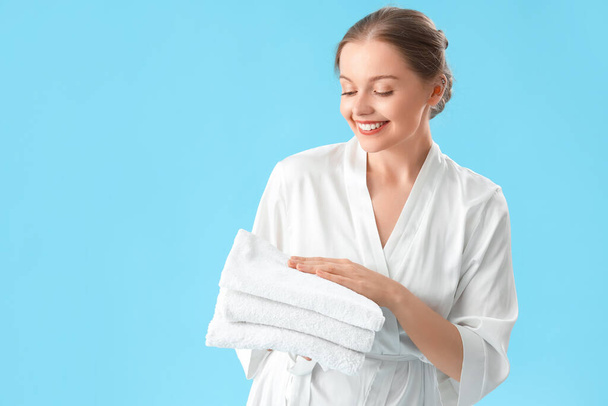 Όμορφη νεαρή γυναίκα με καθαρές πετσέτες σε μπλε φόντο - Φωτογραφία, εικόνα